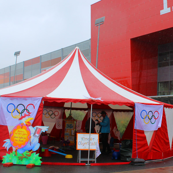 Zeltaktion Kinderolympiade im rot-weiß gestreiften Zirkuszelt.