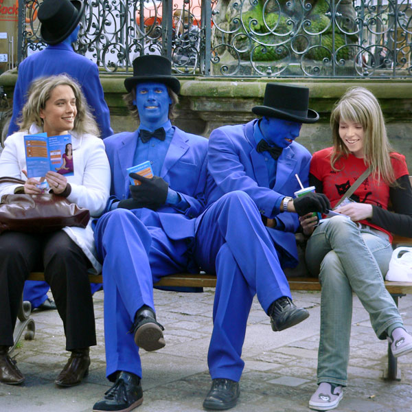 Zwei Blaumänner sitzen in Fußgängerzone neben zwei Frauen auf einer Bank.