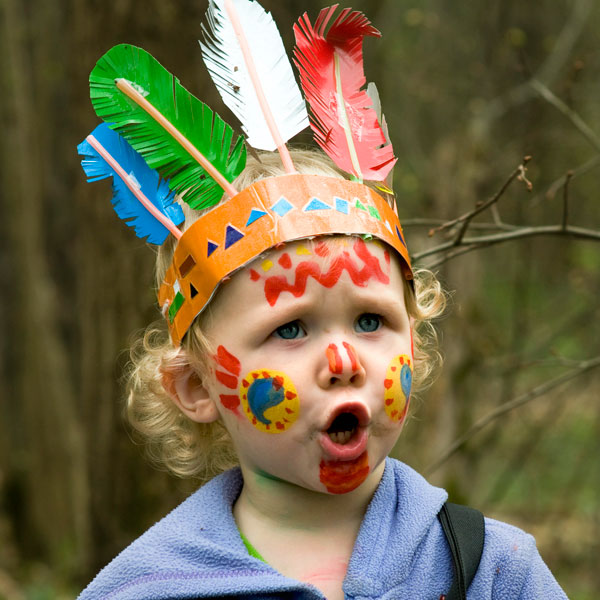 Kind mit geschminktem Indianer Gesicht und Indianer Kopfschmuck.