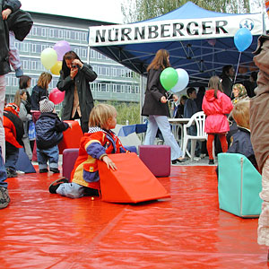 Kinder spielen auf rotem Manegenteppich mit bunten Riesenbausteinen.