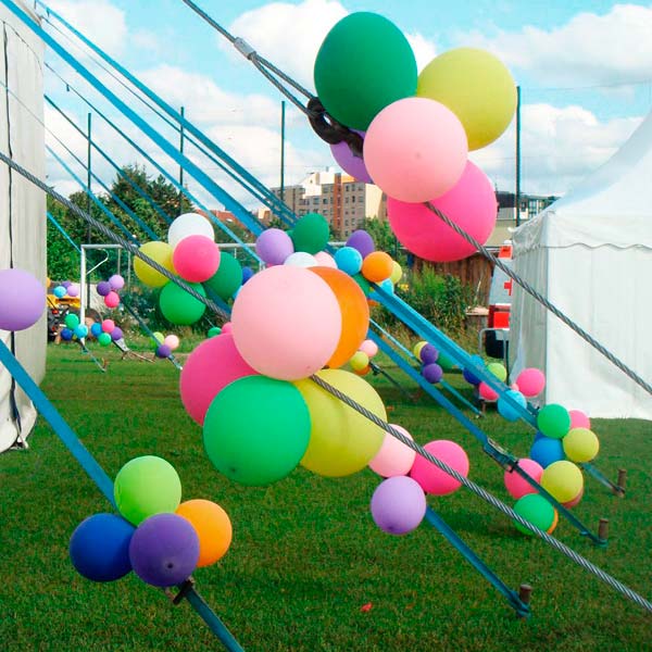 Bunte Luftballons, die in Gruppen an Seile eines Zelts gebunden wurden.