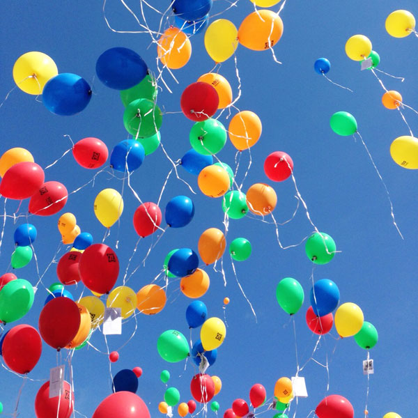 Unzählige bunte Luftballons fliegen in den Himmel.