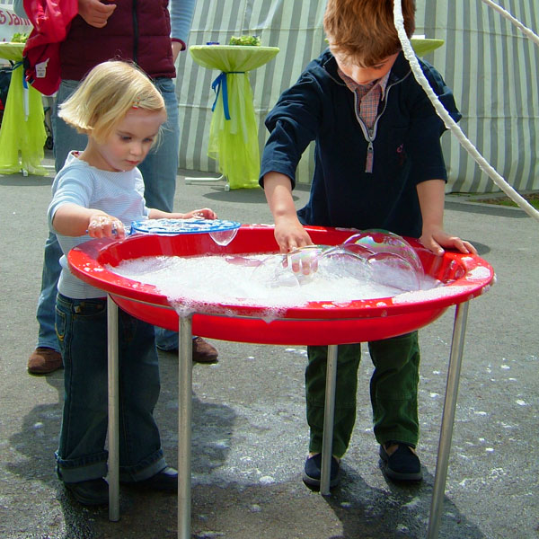 Kinder an einem Becken mit Seifenwasser für Riese-Seifenblasen bei einer Seifenblasen-Aktion.