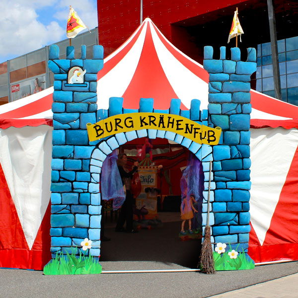 Ritterburg-Eingangsportal vor dem Eingang des rot-weiß gestreiften Zirkuszelts.