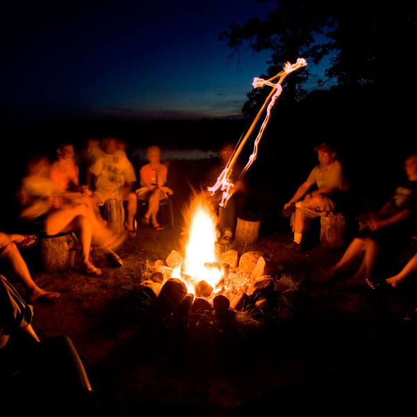 Eine Gruppe Menschen sitzt um ein Lagerfeuer herum.