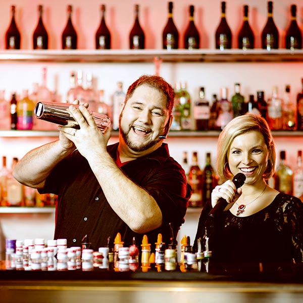 Singing Barkeeper mit Sängerin hinter Cocktailbar.