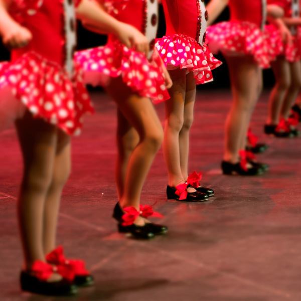Gruppe junger Tänzerinnen auf der Bühne in roten Kleidern.