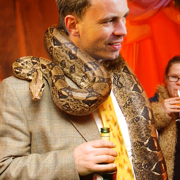 Gast einer Schlangenshow mit Schlange um seinen Hals.