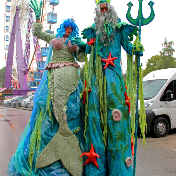 Stelzenläufer als Nixe und Poseidon kostümiert auf dem Nürnberger Volksfest.