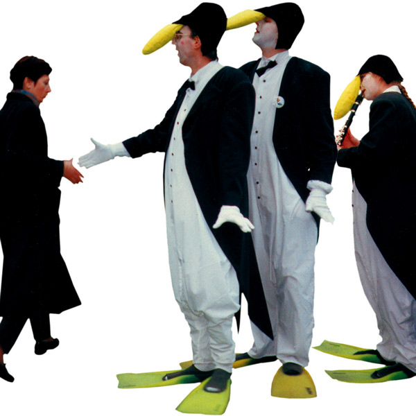 Walkact Künstler als Pinguine begrüßen Passantin.