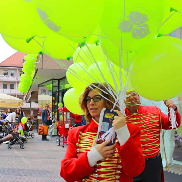 Promoterin in Zirkusjacke mit grüner Luftballontraube.