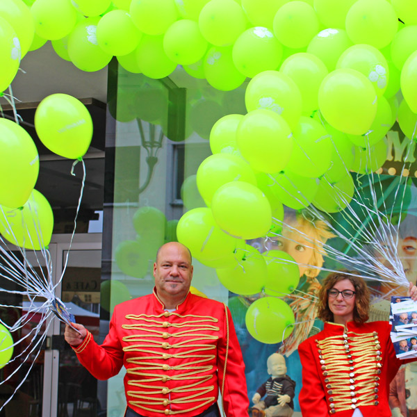 Zwei Promoter in Zirkusjacke mit grünen Ballontrauben.
