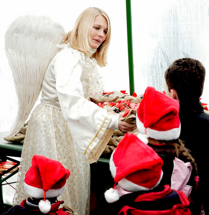 Animateurin im Engelkostüm überreicht Geschenke an Kinder.