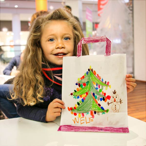 Kind hält selbst bemalte Tüte auf einer Bastelaktion für Kinder.