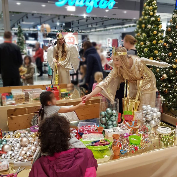 Weihnachts-Bastelaktion mit Kindern und Promoterin im Christkin-Kostüm.