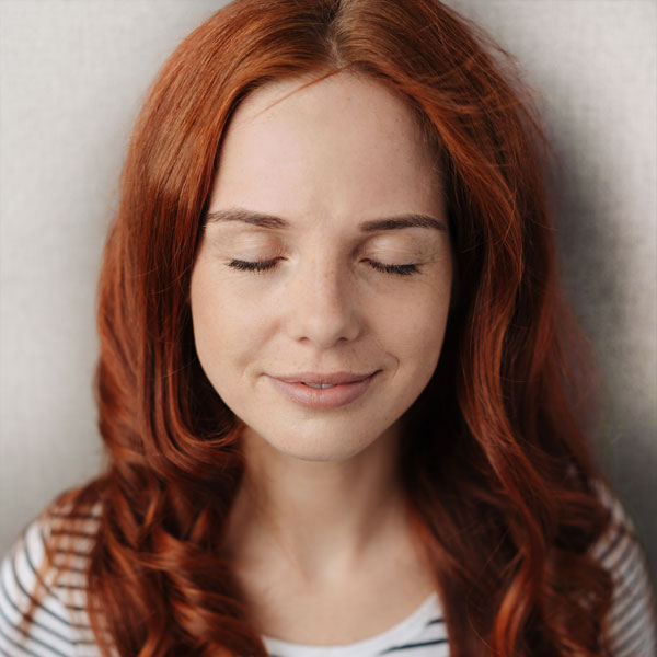 Eine junge Frau lächelt entspannt nach einer Craniosacral-Behandlung