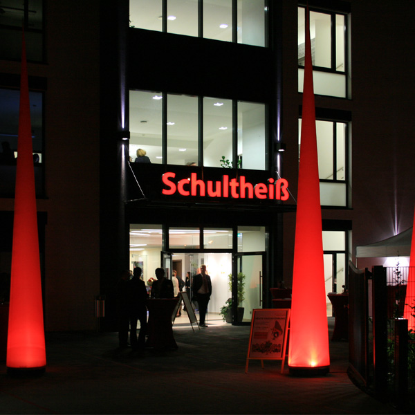 Rote leuchtende Aircones als Eingangsdekoration vor Firmengebäude  nach Sonnenuntergang.