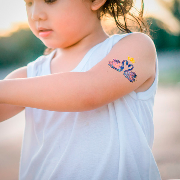 Kleines Mädchen mit einem Glitzertattoo auf dem Arm-
